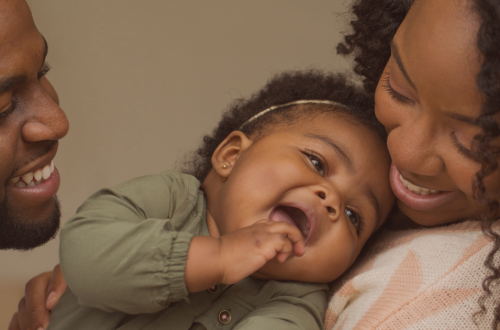 bébé heureux dans les bras de ses parents - théorie de l'attachement