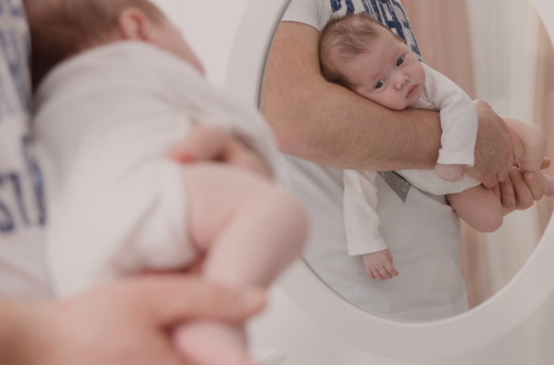 Bébé en position panthère dans les bras de son parent pour soulager ses coliques du nourrisson