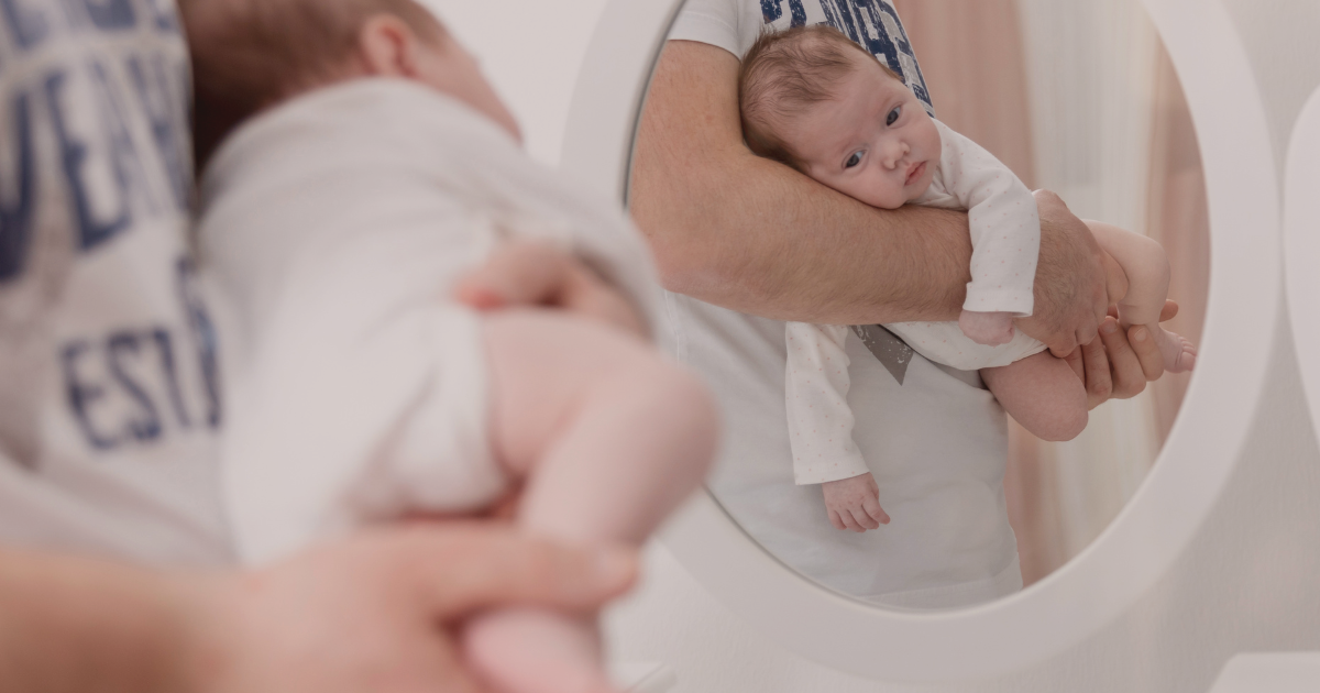 Bébé en position panthère dans les bras de son parent pour soulager ses coliques du nourrisson