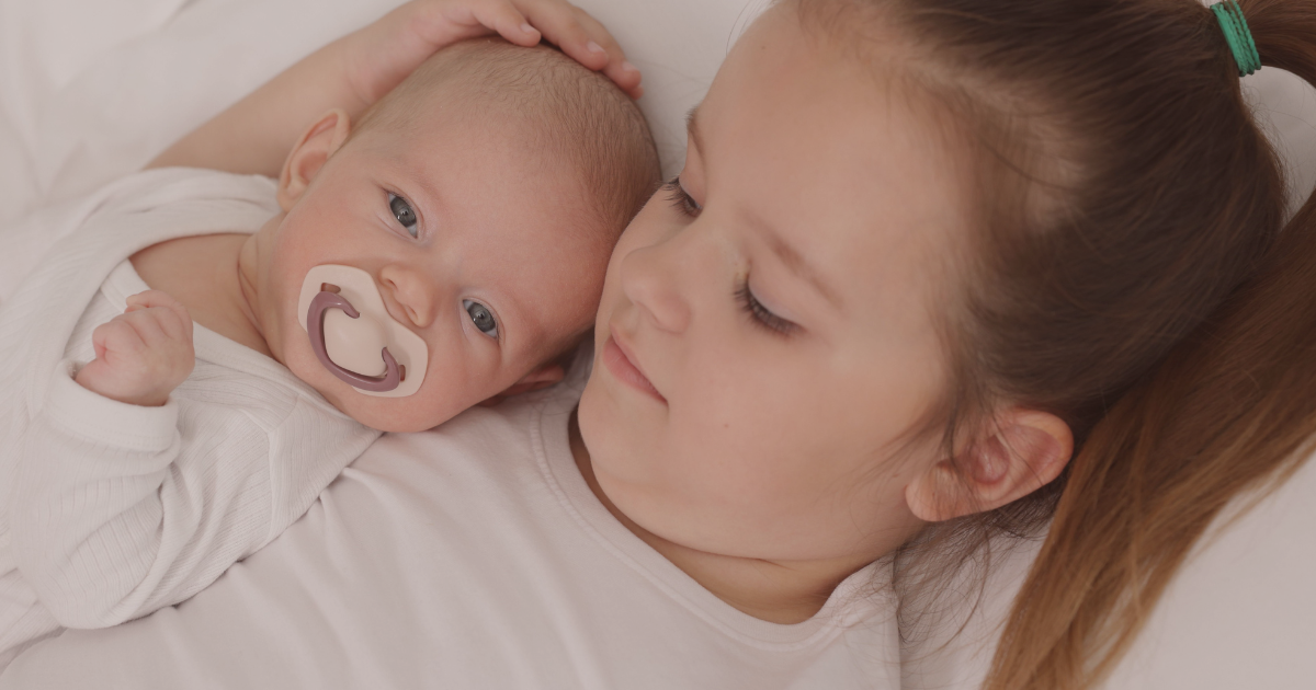 arrivée d'un deuxième enfant dans la famille grande soeur qui fait un calin au nouveau-né